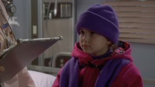 A very young Milana Vayntrub wearing warm clothes and a hat in ER