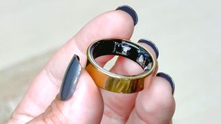 The Samsung Galaxy Ring in a user's hand with blue painted fingernails