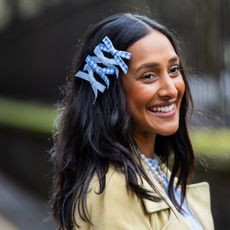 Zeena Shah wearing blue bows in hair with shiny brunette waves thanks to the best hair oils