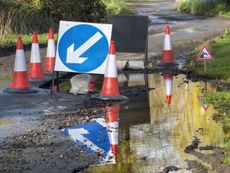 Pothole with warning signs on country lane UK