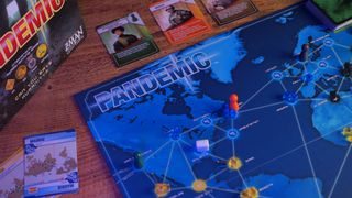 Pandemic board, cards, and tokens on a wooden table