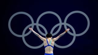 Yiwen Chen preparing a dive before the Olympic ring symbol.