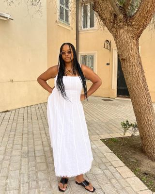 Woman in Saint-Tropez wearing a white maxi dress, black sandals, and sunglasses