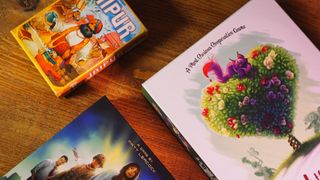 Jaipur, Pandemic, and Paint the Roses boxes on a wooden table, seen from above