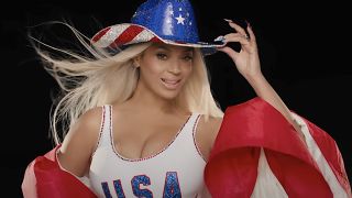 Beyonce tipping a cowboy hat wearing a USA shirt in her ad for the 2024 Summer Olympics