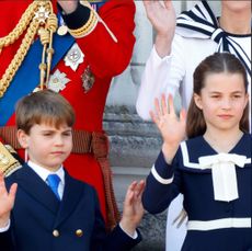 Prince Louis and Princess Charlotte wearing navy and waving on the balcony of Buckingham Palace with their parents behind 