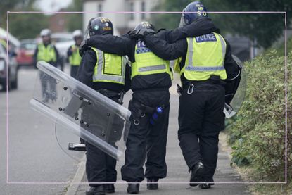 Three riot police with their backs to the camera and their arms around each other