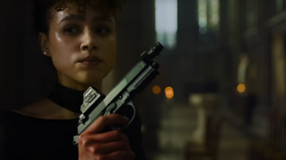 Nathalie Emmanuel holding a gun while taking cover