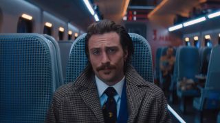 Aaron Taylor Johnson sitting in his seat, dressed sharply in Bullet Train.