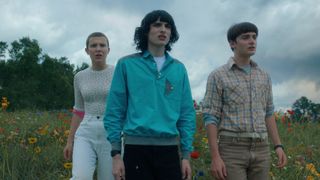 Eleven, Mike, and Will (L-R) stand in a field in "Stranger Things" season 4 