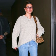 Hailey bieber wears a henley sweater with jeans and a leopard print bag in los angeles for her wedding anniversary dinner