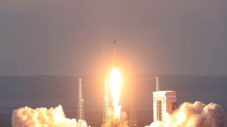 a rocket launches at dusk above a plume of fire and smoke in the desert