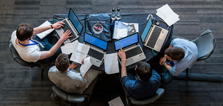 White males gather around computers