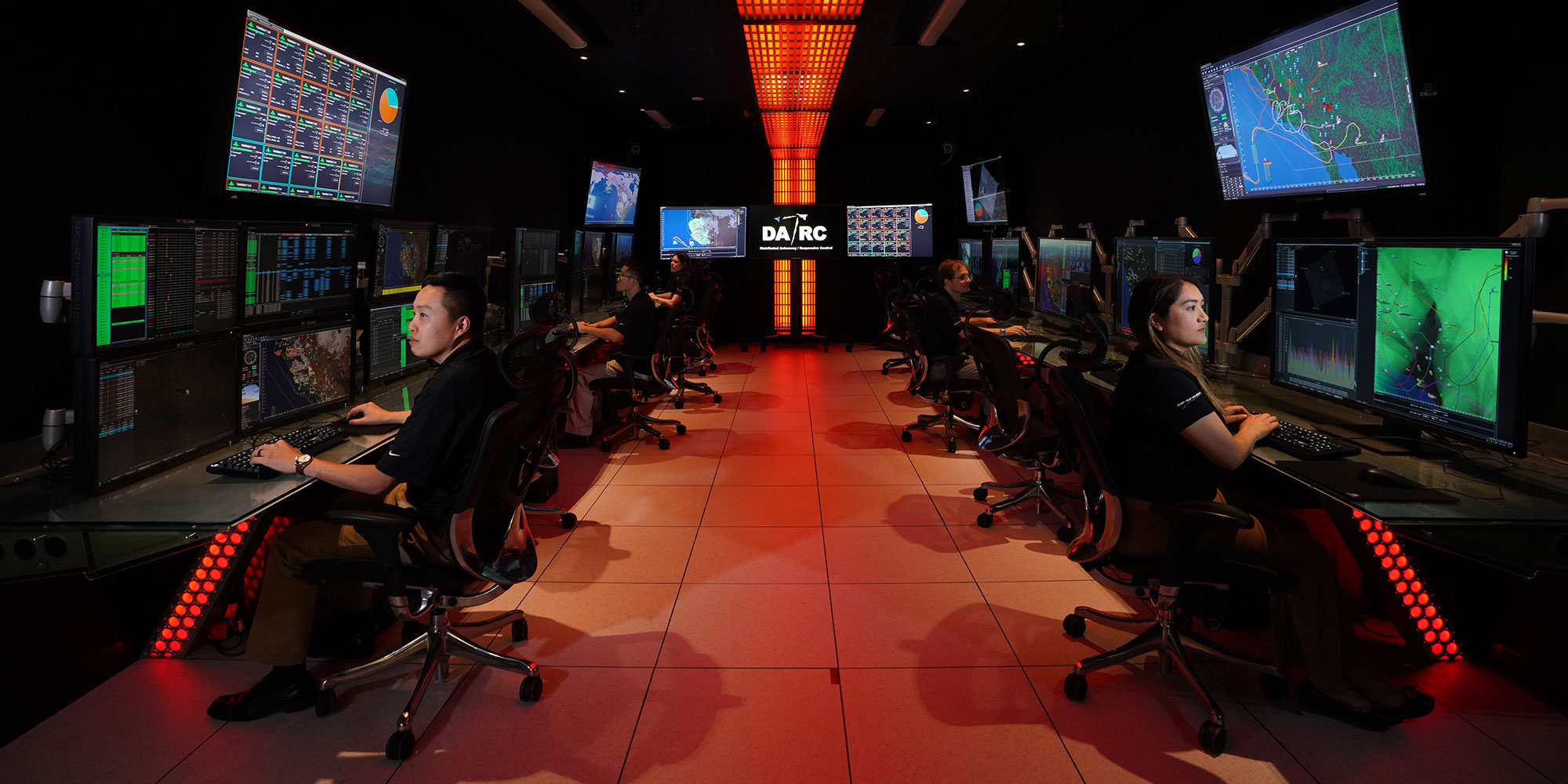 men and women on computers in large room