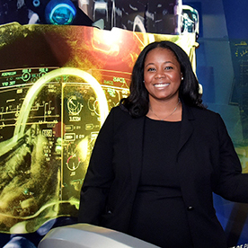 Black woman stands smiling in front of banner