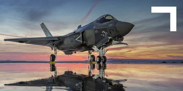 fighter jet at rest on dry lake bed during sunset