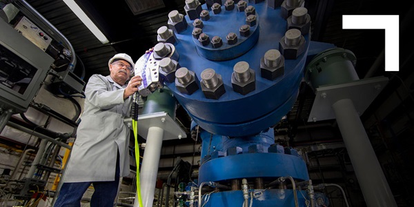 man in front of very large blue gear