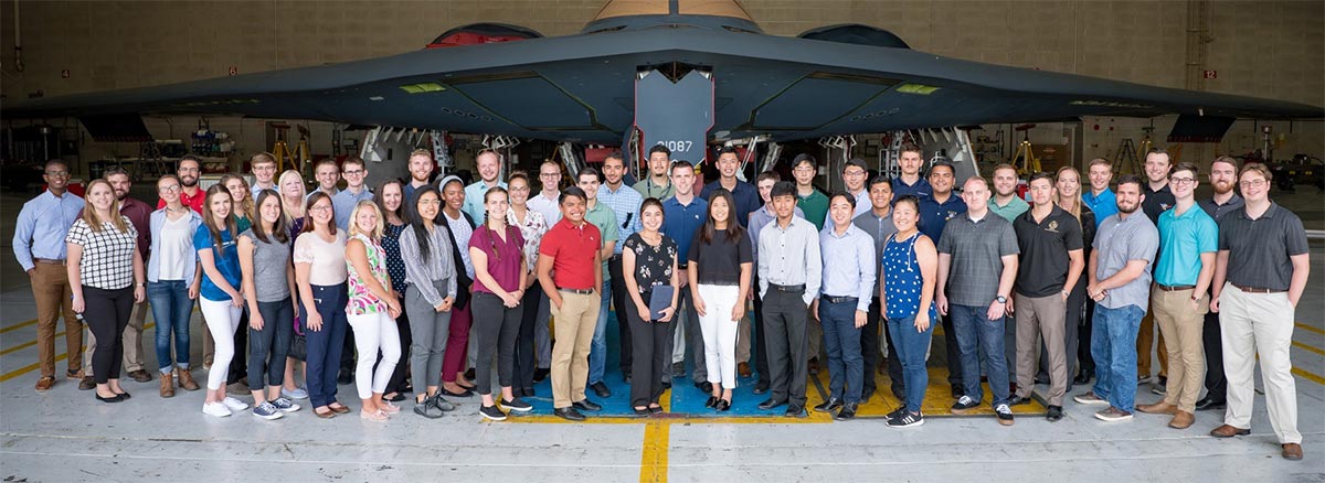 large group of people posing in front of aircraft