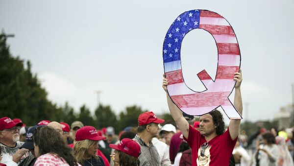 Adepto do movimento QAnon elevando cartaz em forma de Q - Sputnik Brasil