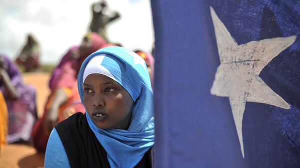 Jovem segura bandeira da Somália durante manifestação de milícia local, na cidade somali de Marka - Sputnik Brasil