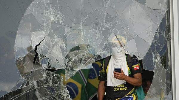 Manifestantes bolsonaristas detrás de janela destruída após invasão do Palácio do Planalto. Brasília (DF), 8 de janeiro de 2023 - Sputnik Brasil