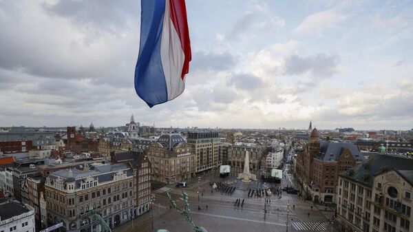 Bandeira holandesa hasteada a meio mastro sobre a Praça Dam, desprovida de espectadores devido a restrições relacionadas ao coronavírus, enquanto o rei holandês Willem-Alexander e a rainha Maxima depositam uma coroa de flores durante uma cerimônia nacional para comemorar os mortos da guerra em Amsterdã, Países Baixos, na terça-feira, 4 de maio de 2021. - Sputnik Brasil