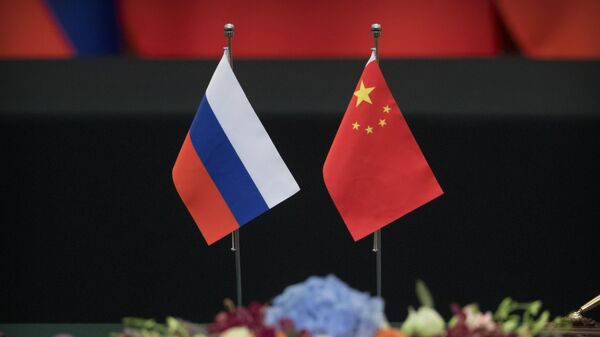 Bandeiras russa, esquerda e chinesa sobre uma mesa antes de uma cerimônia de assinatura no Grande Salão do Povo em Pequim, sexta-feira, 8 de junho de 2018. A cooperação entre a Rússia e a China está em alta, disse o presidente russo Vladimir Putin seu homólogo chinês, Xi Jinping, em uma reunião na sexta-feira antes de uma cúpula com seus dois países e seis estados asiáticos. - Sputnik Brasil