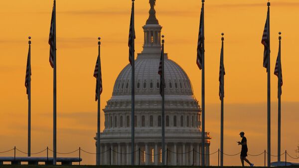 Pedestre caminha ao nascer do sol por bandeiras dos EUA no National Mall e passa pelo edifício do Capitólio norte-americano, em Washington D.C. EUA, 7 de novembro de 2022 - Sputnik Brasil