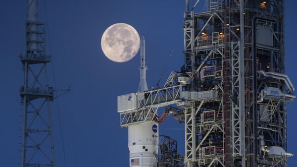 Lua cheia vista atrás do Sistema de Lançamento Espacial (SLS, na sigla em inglês) Artemis I e da espaçonave Orion, no Complexo de Lançamento 39B, no Centro Espacial Kennedy, da NASA. Flórida, 14 de junho de 2022 - Sputnik Brasil