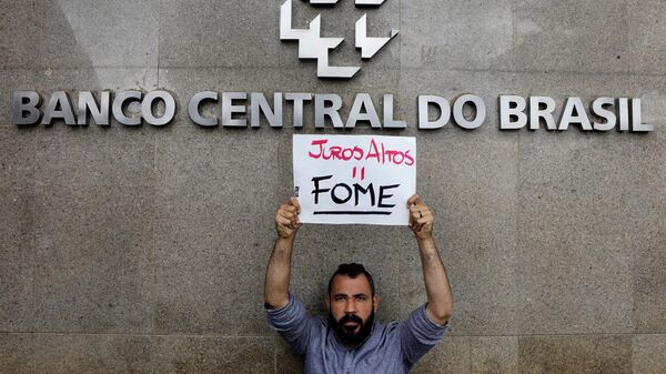 Um manifestante segura uma placa que diz: Juros altos é igual a fome em frente ao Banco Central. Brasília, 21 de março de 2023 - Sputnik Brasil