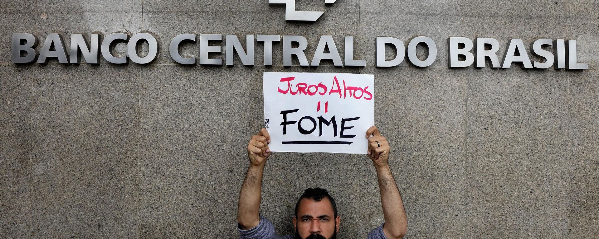 Um manifestante segura uma placa que diz: Juros altos é igual a fome em frente ao Banco Central. Brasília, 21 de março de 2023 - Sputnik Brasil, 1920, 04.09.2024