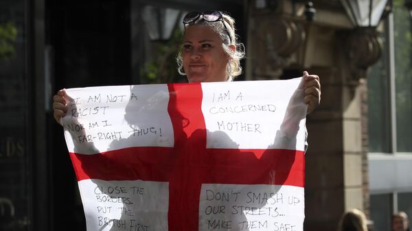 Mulher segura bandeira da Inglaterra com dizeres contra a migração no país durante protesto que gerou onda de violência. Newcastle, 10 de agosto de 2024 - Sputnik Brasil