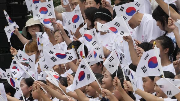 Sul-coreanos agitam bandeiras nacionais durante uma cerimônia para celebrar o Dia da Libertação da Coreia do domínio colonial japonês em 1945, em frente ao pavilhão Bosingak em Seul, Coreia do Sul, 15 de agosto de 2024 - Sputnik Brasil