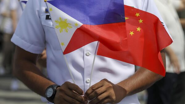 Membro da Guarda Costeira filipina segura bandeiras das Filipinas e da China durante chegada de navio de treinamento naval chinês Qi Jiguang, que participa de visita de boa vontade no porto de Manila. Filipinas, 14 de junho de 2023 - Sputnik Brasil