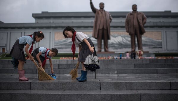 Crianças limpam os degraus perto dos monumentos de Kim Jong-il e Kim Il-sung na Coreia do Norte, no âmbito dos festejos do Dia da Vitória - Sputnik Brasil