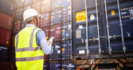 A supply chain professional overseeing cargo containers of components; find out how the coronavirus has impacted the supply chain at Sourcengine.