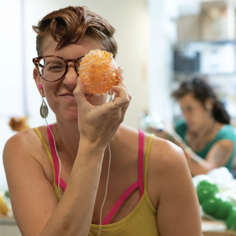 person holding up an orange to their face and looking at the camera