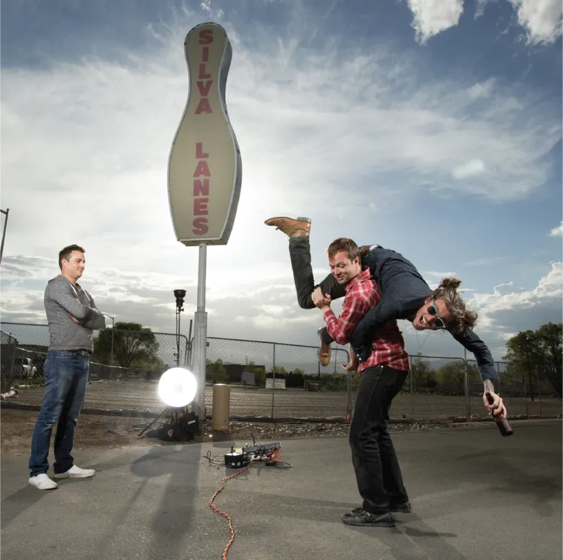 Two people standing in front of a bowling pin shaped sign, the site of Meow Wolf Santa Fe