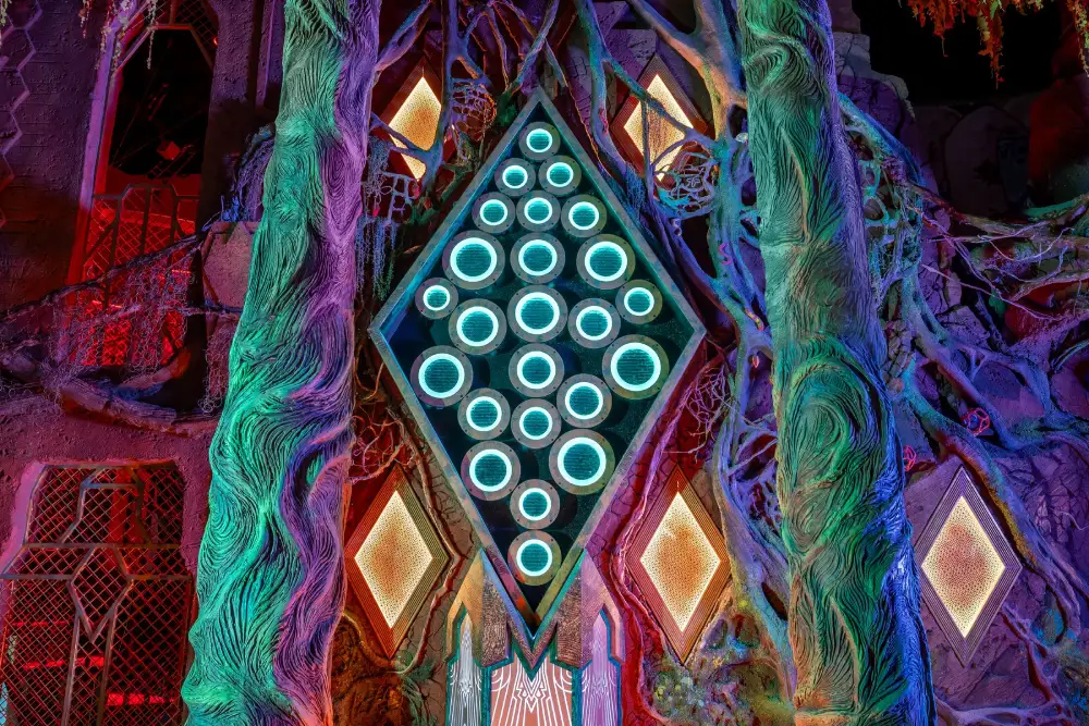 A neon colored diamond shape hangs on an interdimensional wall at Meow Wolf Houston.