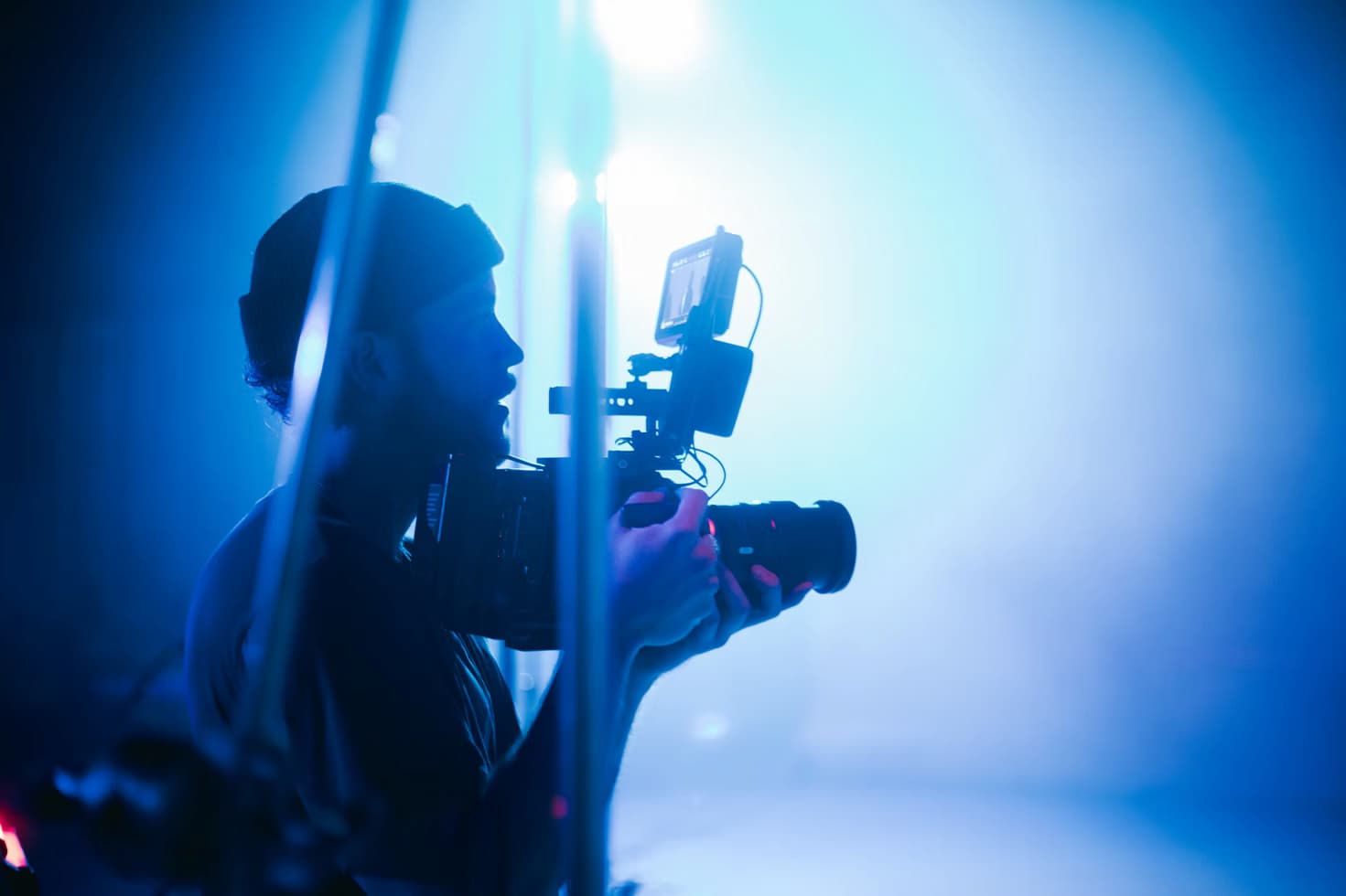 Cameraman wearing a beanie in a photo studio in dramatic blue light