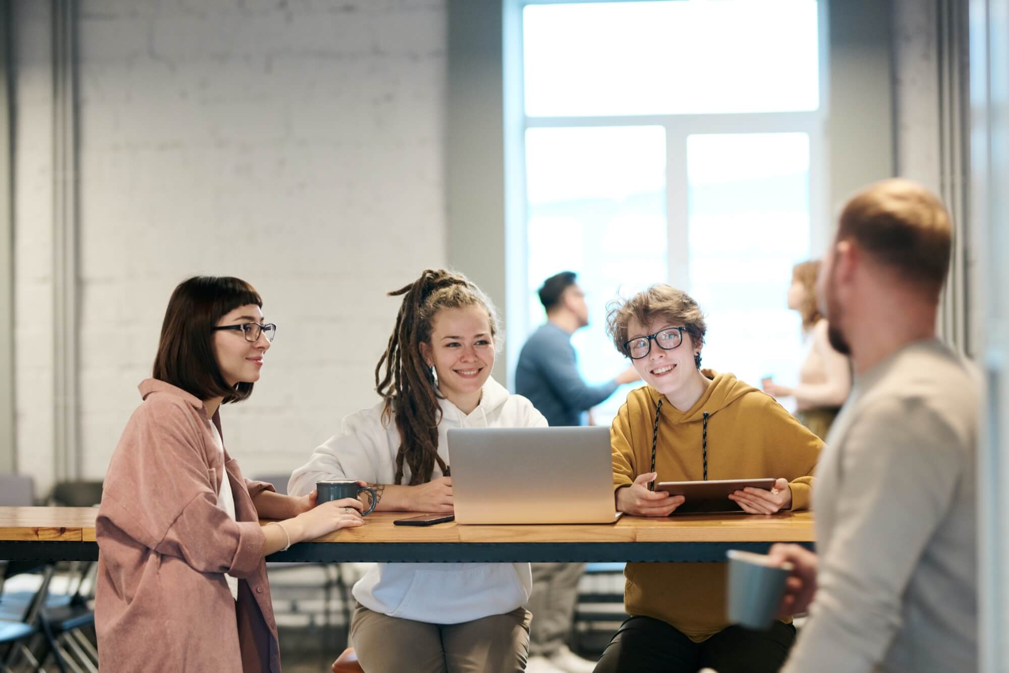 3 young coworkers working and smiling at fellow coworker