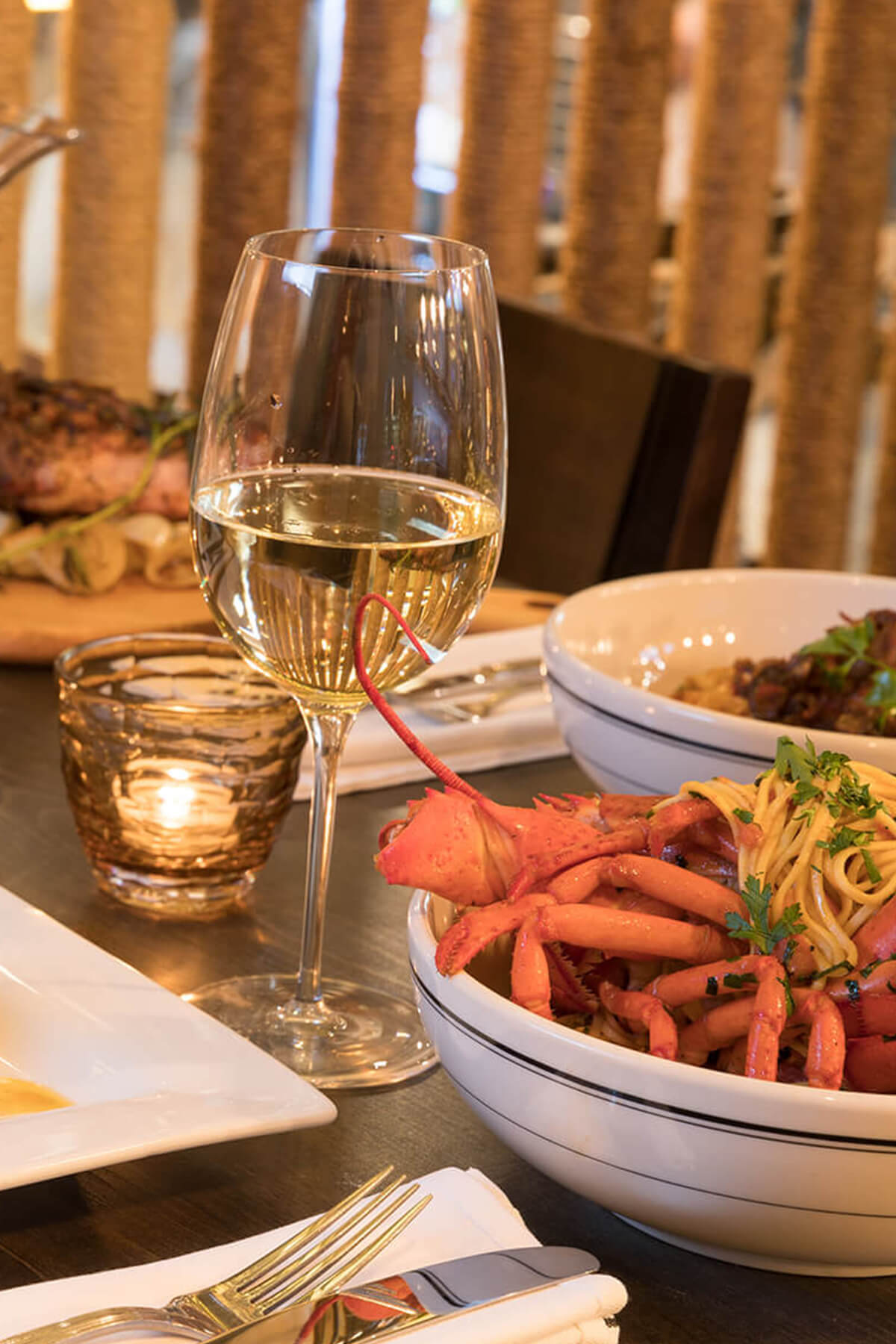 dining table with a glass of wine and lobster