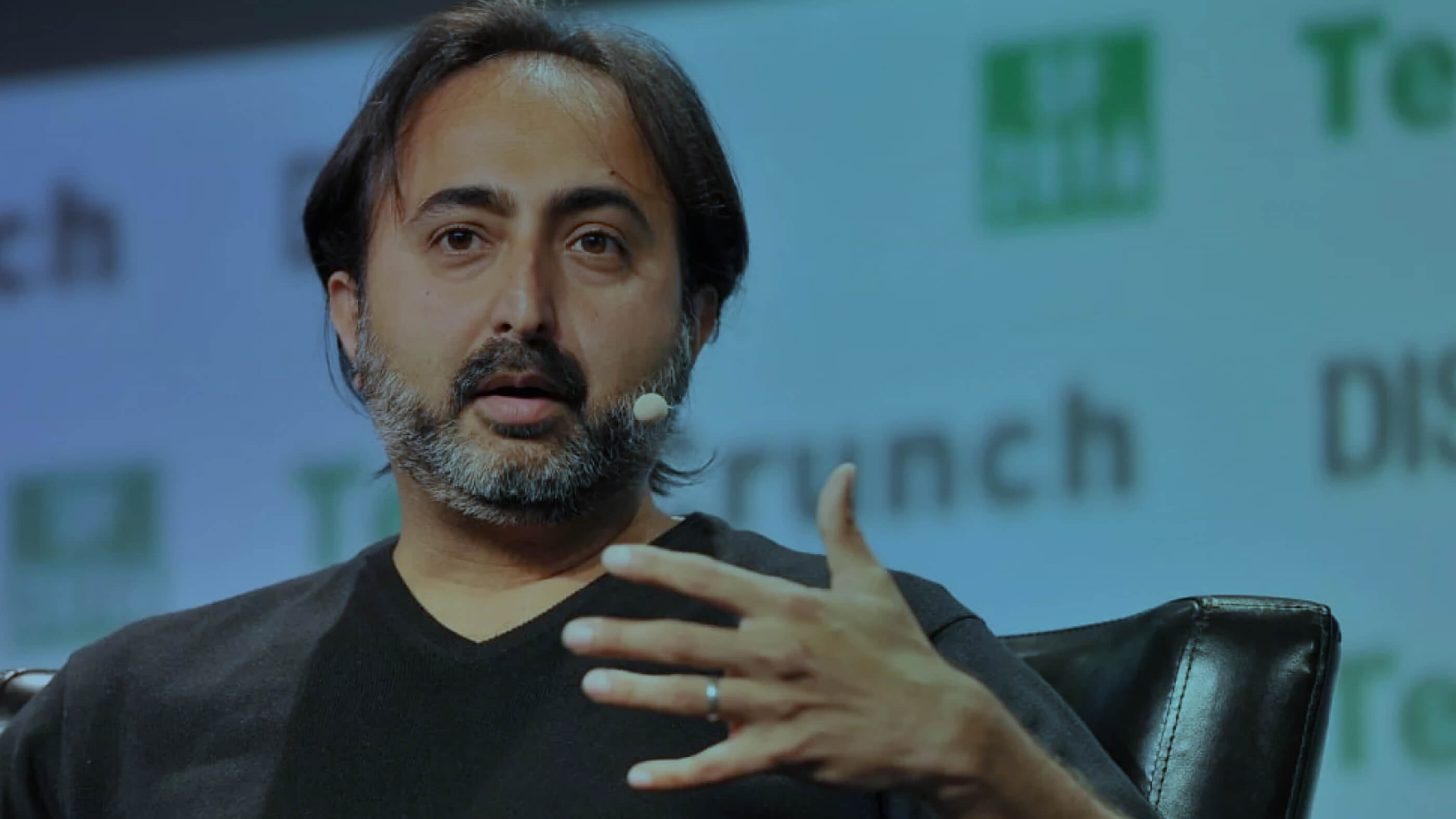 Close-up of Hemant Taneja speaks at TechCrunch event, gesturing mid-speech.