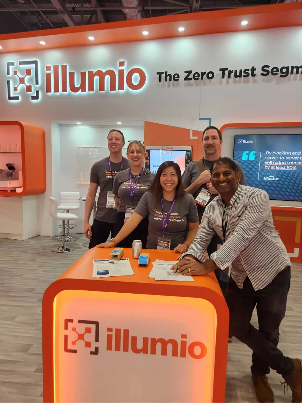 A smiling team of Illumio brand ambassadors eager to explain Zero Trust Segmentation at a convention.