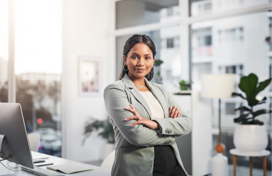 A woman in a business suit standing in front of a laptop.