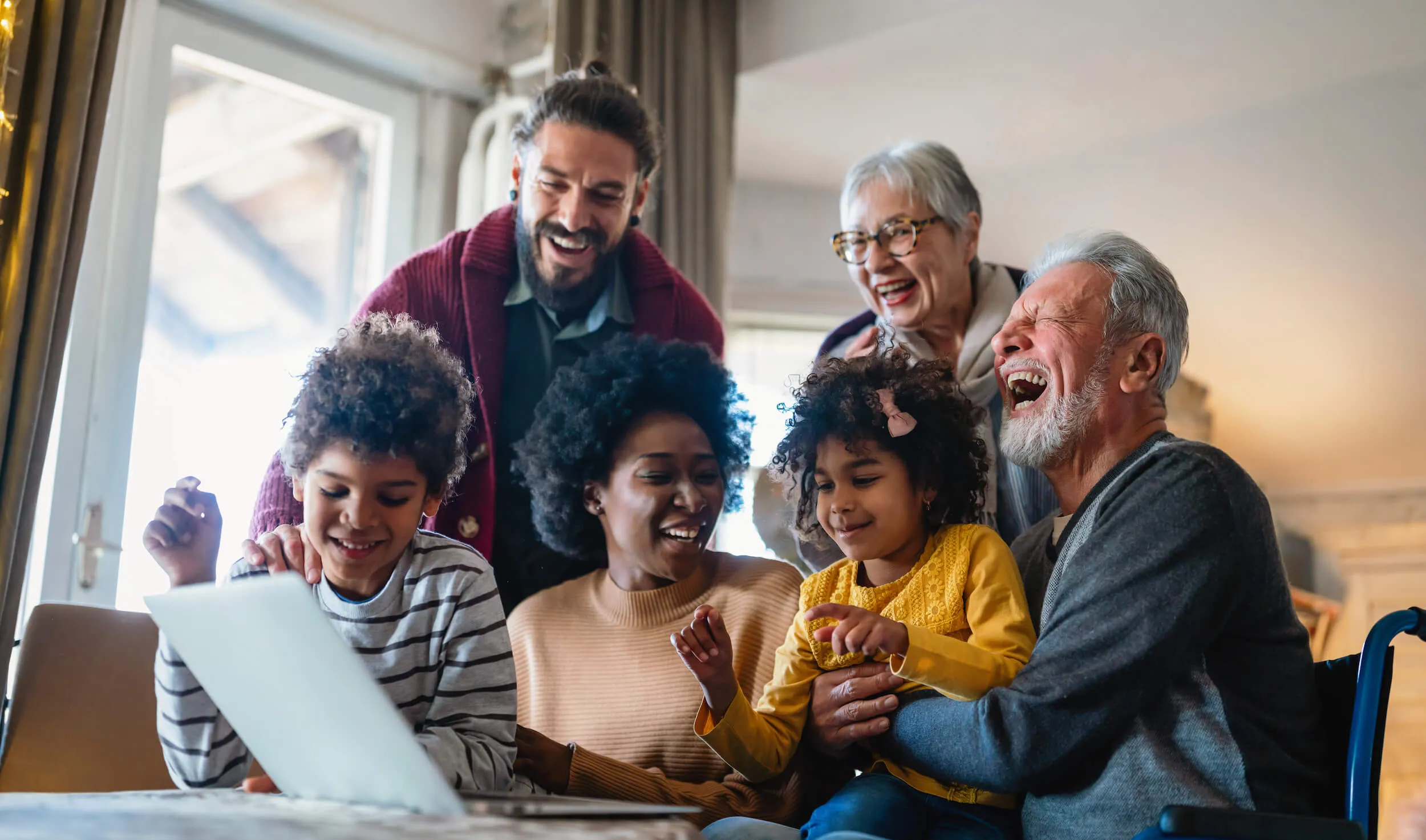 family laughing together and watching something on the laptop