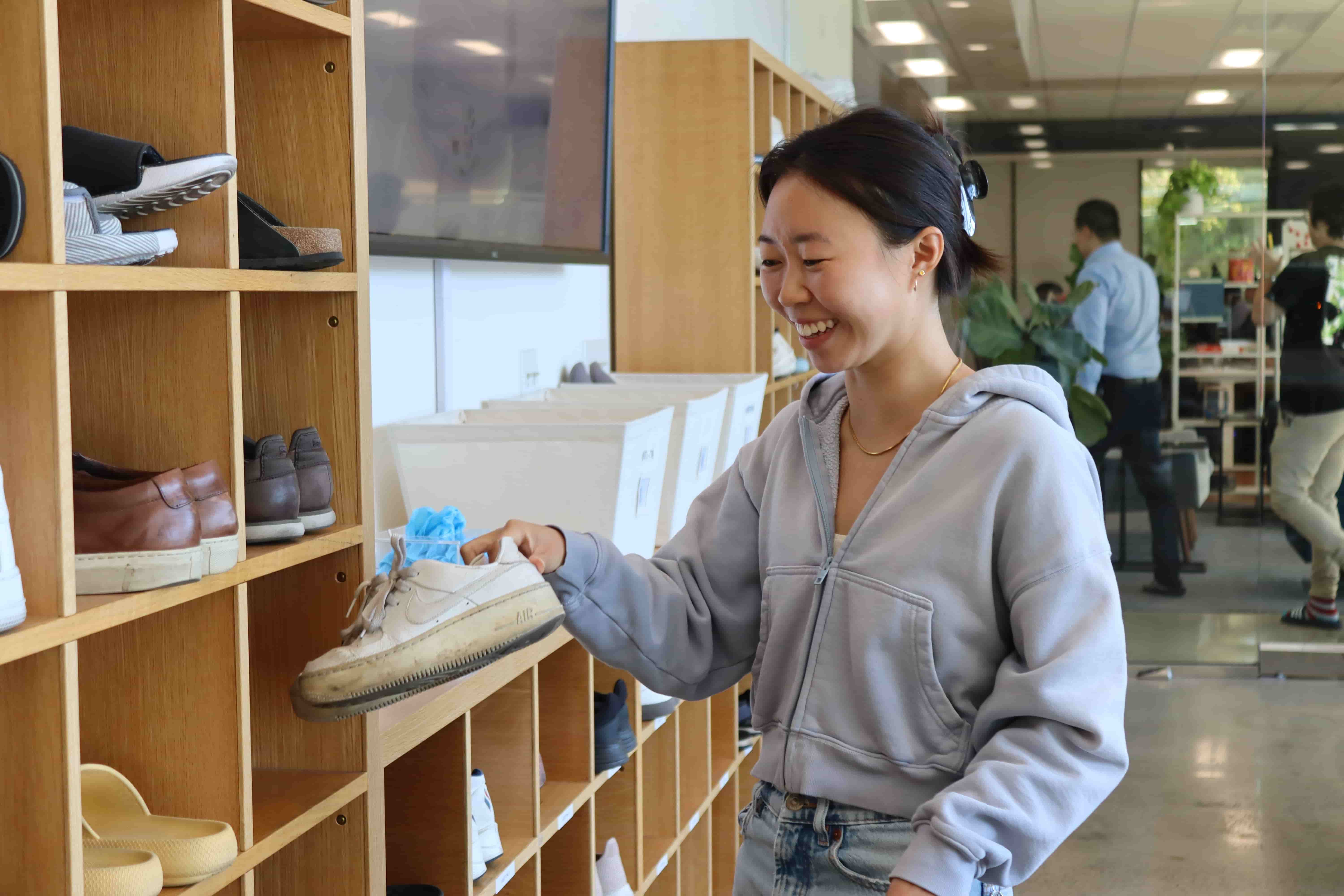 Jasmine Wu placing athletic shoes on a shelf in the lobby of Applied Intuition.