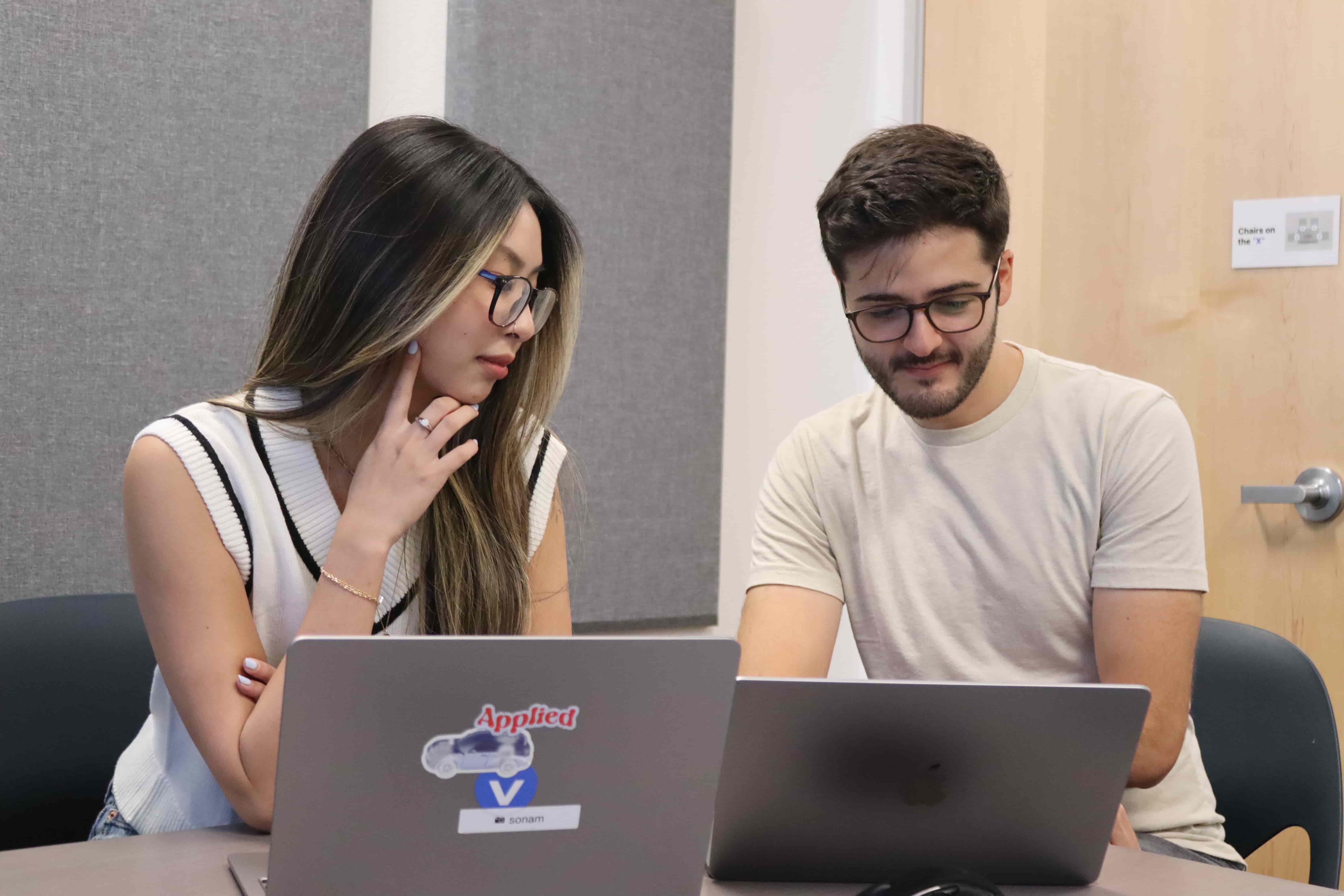 Sonam Huang and Richie Goulazian working on laptops, with Sonam (on the left) looking at Richie's screen.