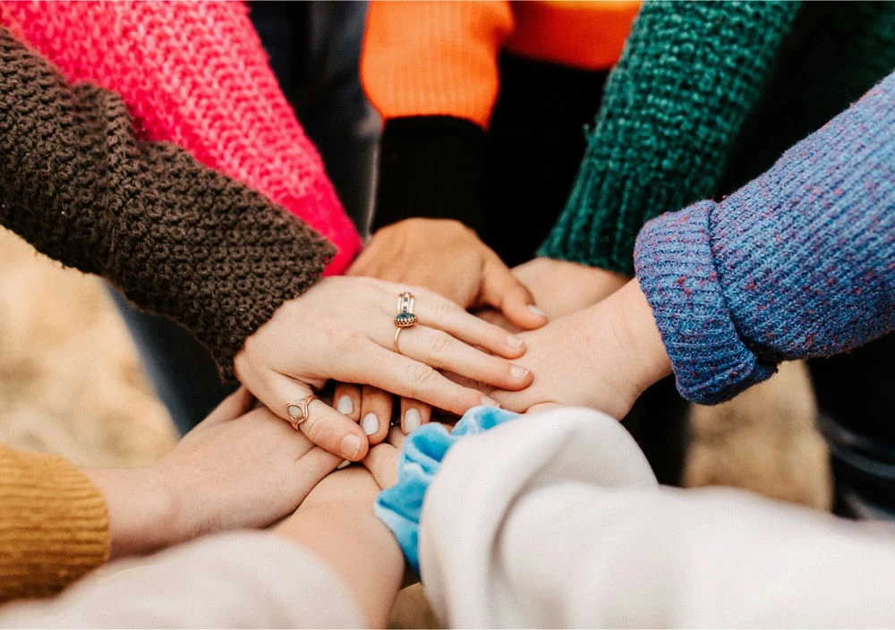 SurePayroll employees put their hands together in a circle to end a meeting about making online payroll easier for small business and household employers.