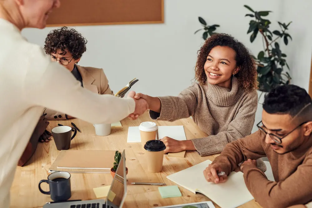 Workers meeting at a conference table to keep up with HR and compliance for small business.